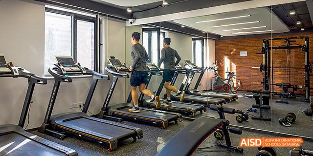A male student from JPED Academy, running on a treadmill in a fitness center.