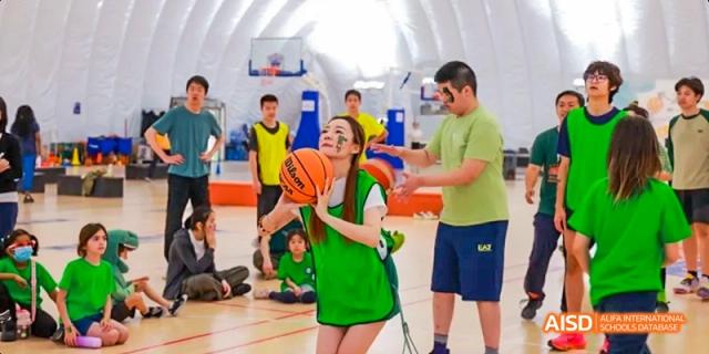 A student from JPED Academy, dribbling a basketball on an indoor court.