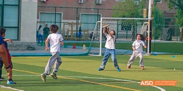 A group of students from JPED Academy, playing soccer on a sports field.