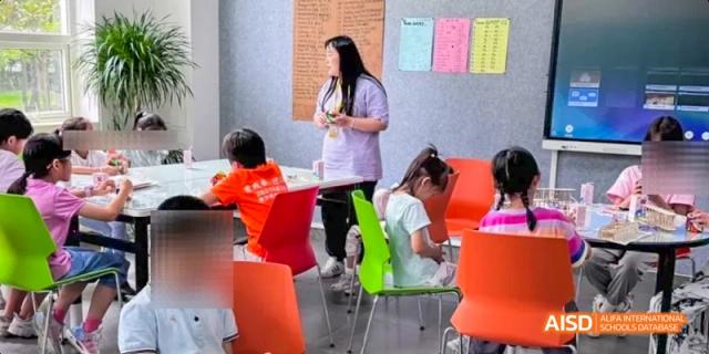 A group of students sitting on colorful chairs while a teacher stands behind them, Léman International School Chengdu