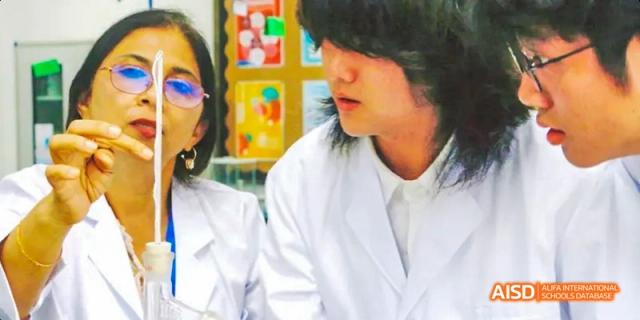 A male student in a lab coat observing an experiment, Léman International School Chengdu