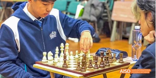 A person's hand moving a chess piece during a game, Léman International School Chengdu