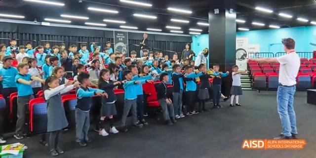 A large group of students in blue shirts posing for a photo outdoors, Léman International School Chengdu