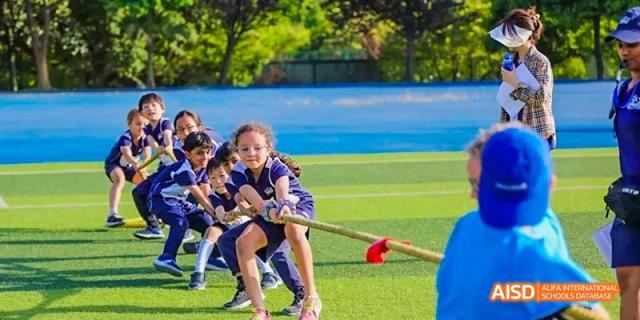 Students participating in a tug-of-war game on a grassy field, Léman International School Chengdu