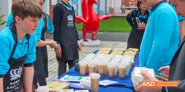 Students serving drinks from a stand at a school fair, Léman International School Chengdu