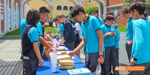 Students at a school fair, serving food from a booth, Léman International School Chengdu