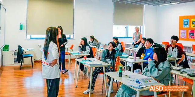 Students attentively listening to a teacher during a class in a bright, spacious classroom at Majestic International College.