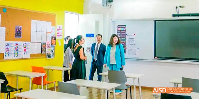 A group of students and staff members greeting visitors in a school hallway at Majestic International College.