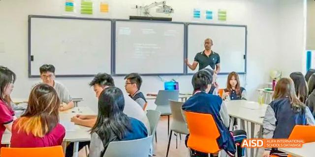 A teacher using a whiteboard to explain a lesson to students in a classroom at Majestic International College.