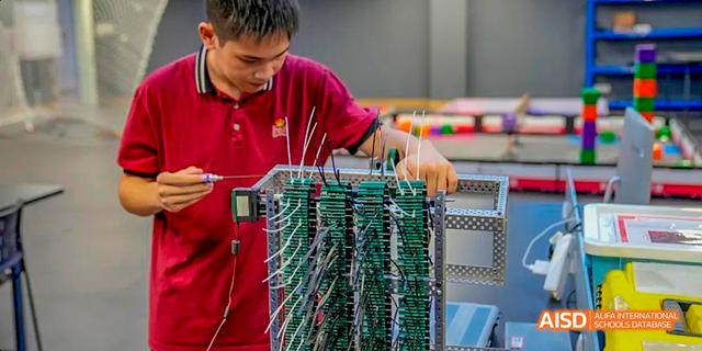 A student working with a complex electronic project with many wires at Majestic International College.
