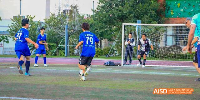 A student in a blue jersey with the number 79 playing soccer on a green field at Majestic International College.