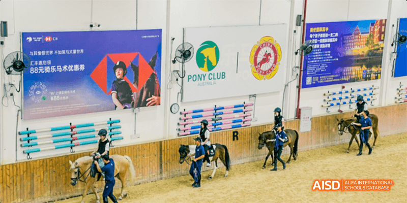 Young students with helmets on small ponies in a horse riding club, a Majestic International College activity.