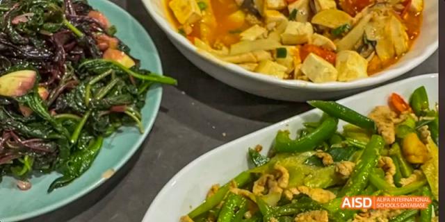 A close-up view of a variety of Chinese dishes, including a stir-fried vegetable dish at Majestic International College.