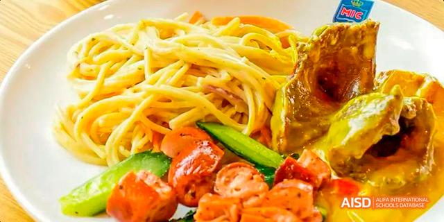 A plate of spaghetti with sausages and sliced cucumbers at Majestic International College.