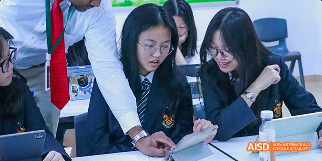 A teacher is helping a student with a tablet in a classroom at Malvern College Chengdu.