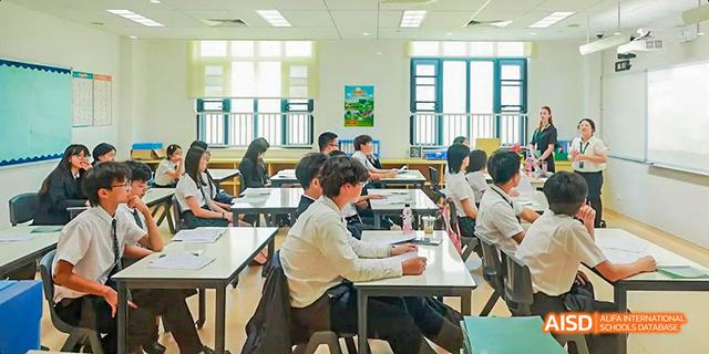 Students are sitting at desks in a classroom, with one student looking at the camera at Malvern College Chengdu.