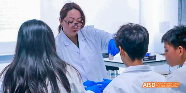 A teacher is guiding a student in a lab coat on a science experiment at Malvern College Chengdu.
