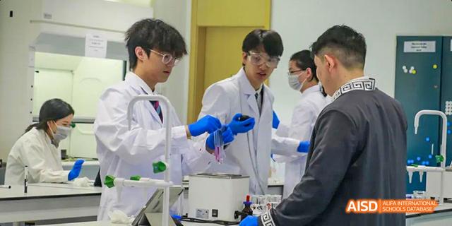 A close-up of students in lab coats and blue gloves working on a science experiment at Malvern College Chengdu.