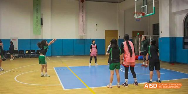 A group of students playing on a blue and yellow court in an indoor gym at Malvern College Chengdu.