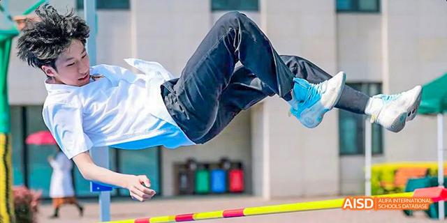A student is holding a javelin, preparing to throw it during a track and field event at Malvern College Chengdu.