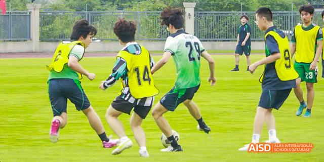 Students are playing soccer on a green field at Malvern College Chengdu.