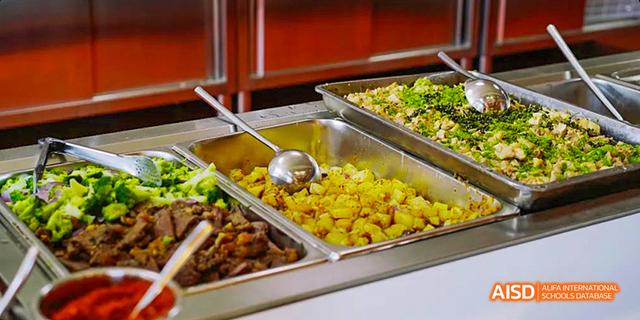 A tray of cooked potatoes and other dishes is displayed in a school cafeteria at Malvern College Chengdu.