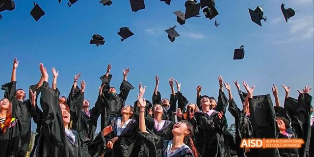 Graduating students in caps and gowns throwing their hats in the air at Maple Leaf International School - Luoyang.