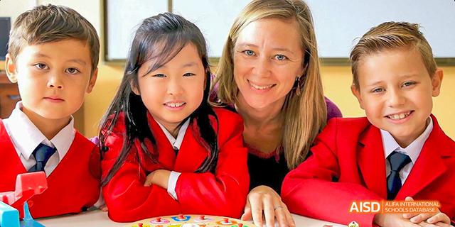 A female teacher with students in red uniforms at Maple Leaf International School - Luoyang.