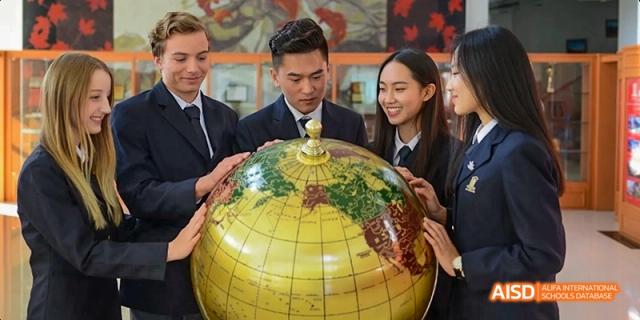A teacher and students looking at a large globe at Maple Leaf International School - Luoyang.