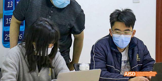 A student and a teacher standing next to a whiteboard at Maple Leaf International School - Luoyang.