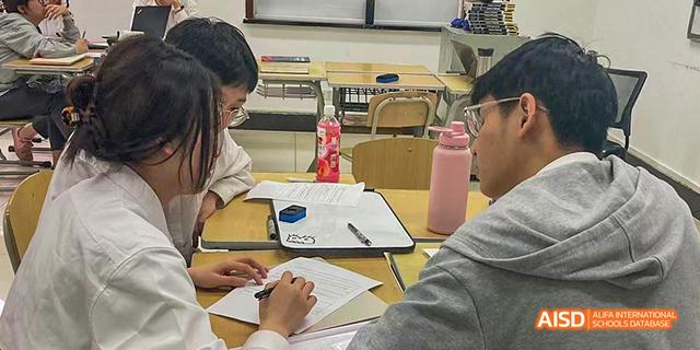 Students writing at their desks in a classroom at Maple Leaf International School - Luoyang.