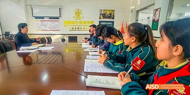 A student in a red uniform writing at a desk at Maple Leaf International School - Luoyang.