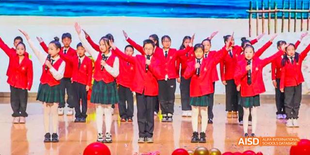 Students performing on stage in red uniforms at Maple Leaf International School - Luoyang.