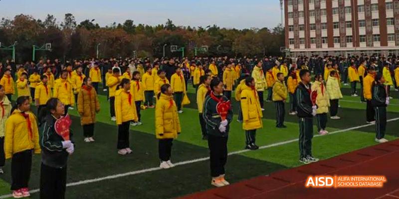 Students standing in a group on a sports field at Maple Leaf International School - Luoyang.