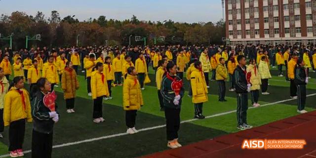Students standing in a group on a sports field at Maple Leaf International School - Luoyang.
