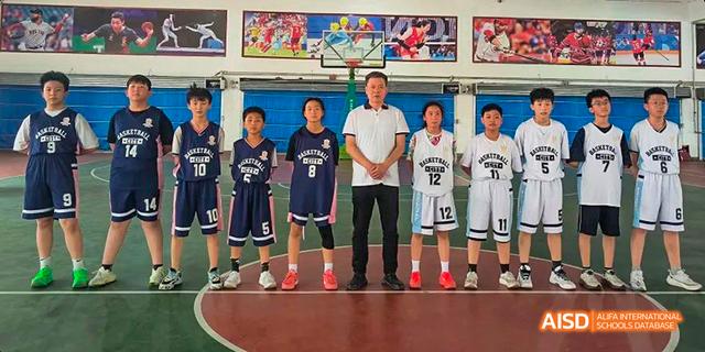 A group of students and a teacher posing on a basketball court at Maple Leaf International School - Luoyang.