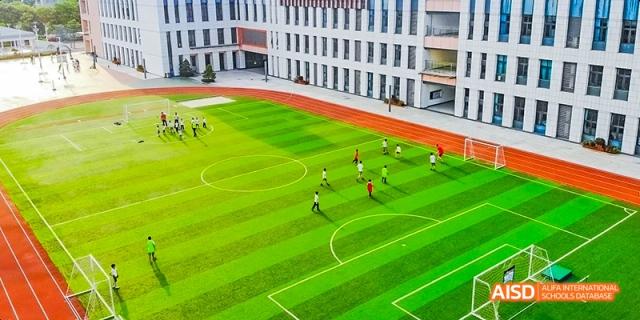 Students playing soccer on a green field at Maple Leaf International School - Luoyang.