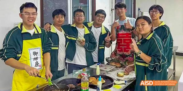 A group of students with a teacher or staff member in a kitchen or food preparation area at Maple Leaf International School - Luoyang.