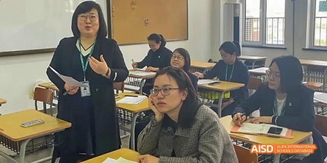 A female student from Maple Leaf International High School - Dalian smiling while sitting at a desk in a classroom.