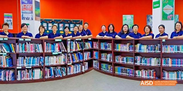 A group of students from Maple Leaf International High School - Dalian are looking at books on a shelf in the library.