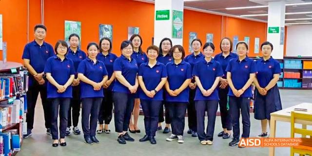 A group of students from Maple Leaf International High School - Dalian in blue uniforms standing together for a photo.
