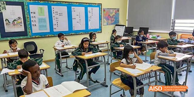 A student from Maple Leaf International High School - Dalian is sitting at a desk and studying in a classroom.