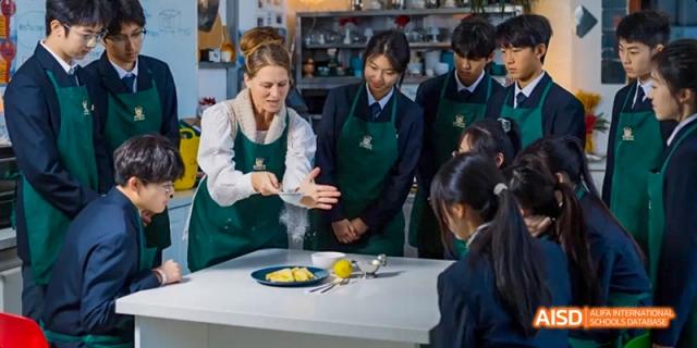A teacher and a group of students from Maple Leaf International High School - Dalian gathered around a table with food.