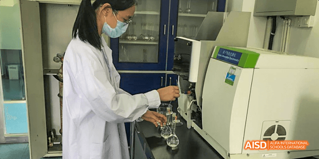 A student from Maple Leaf International High School - Dalian pouring a liquid from a flask into a beaker.