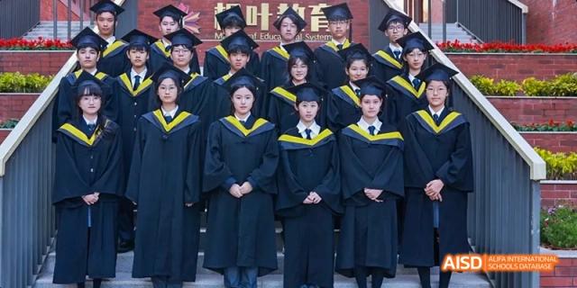 Students from Maple Leaf International High School - Dalian in graduation gowns and hats are posing for a group photo.
