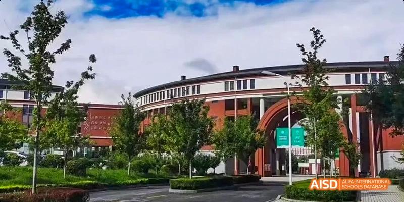 A red brick school building with a circular driveway and trees at Maple Leaf International High School - Dalian