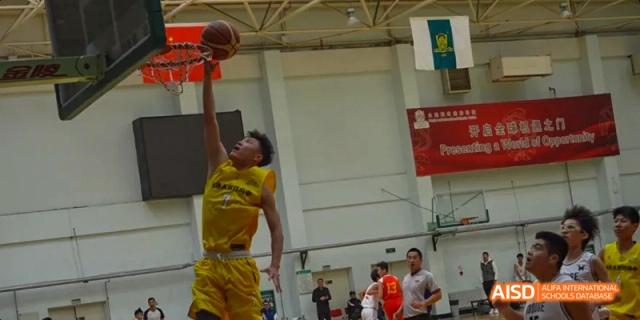 A student attempting a slam dunk during a basketball game at Maple Leaf International High School - Dalian