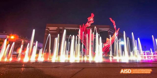 A fountain with red lights at night at Maple Leaf International High School - Dalian