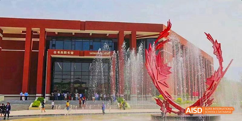 A fountain with red statues and a modern building in the background at Maple Leaf International High School - Dalian