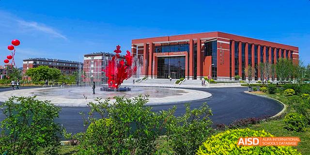 An exterior view of a modern school building and a statue at Maple Leaf International High School - Dalian